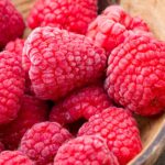 Frozen raspberries on wooden background.